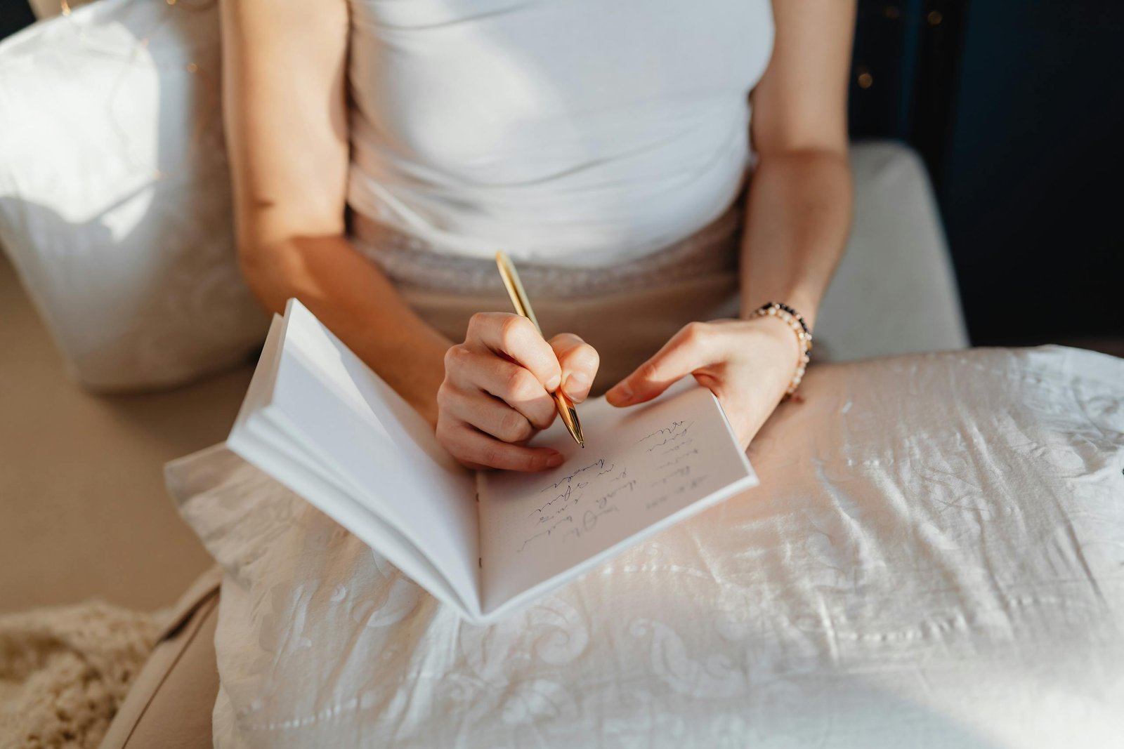 Close-up of a woman writing in a journal while sitting comfortably indoors.