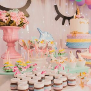 A vibrant unicorn-themed birthday party setup with cakes, cupcakes, and decorations.