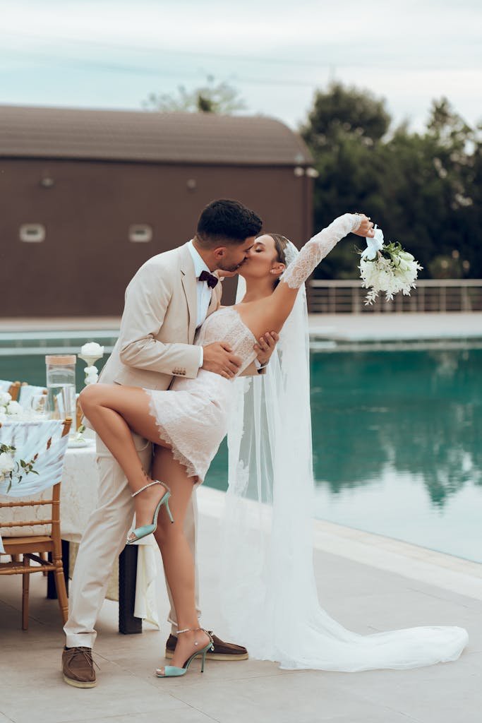 Bride and groom in an intimate kiss by the poolside, capturing love and celebration.