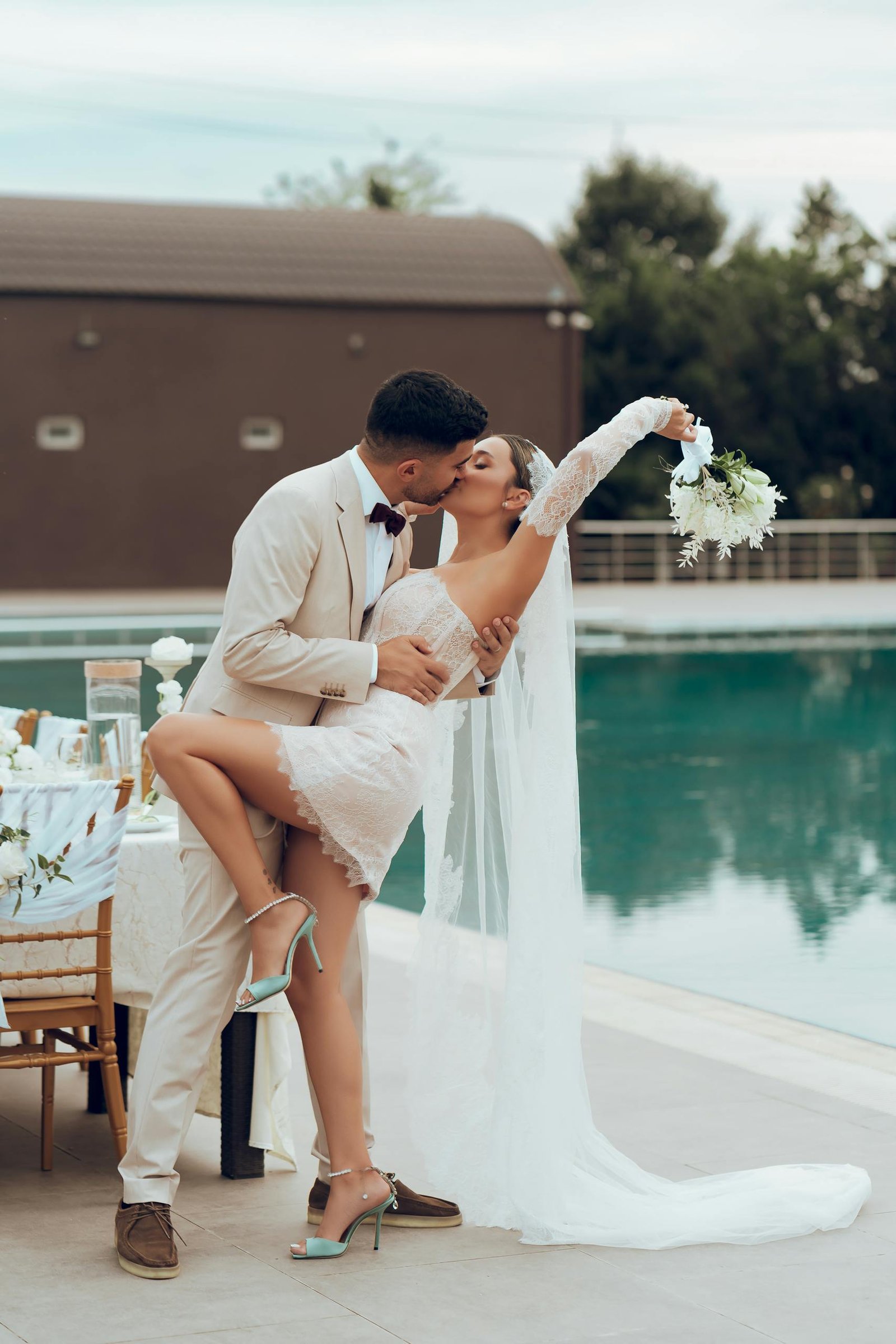 Bride and groom in an intimate kiss by the poolside, capturing love and celebration.